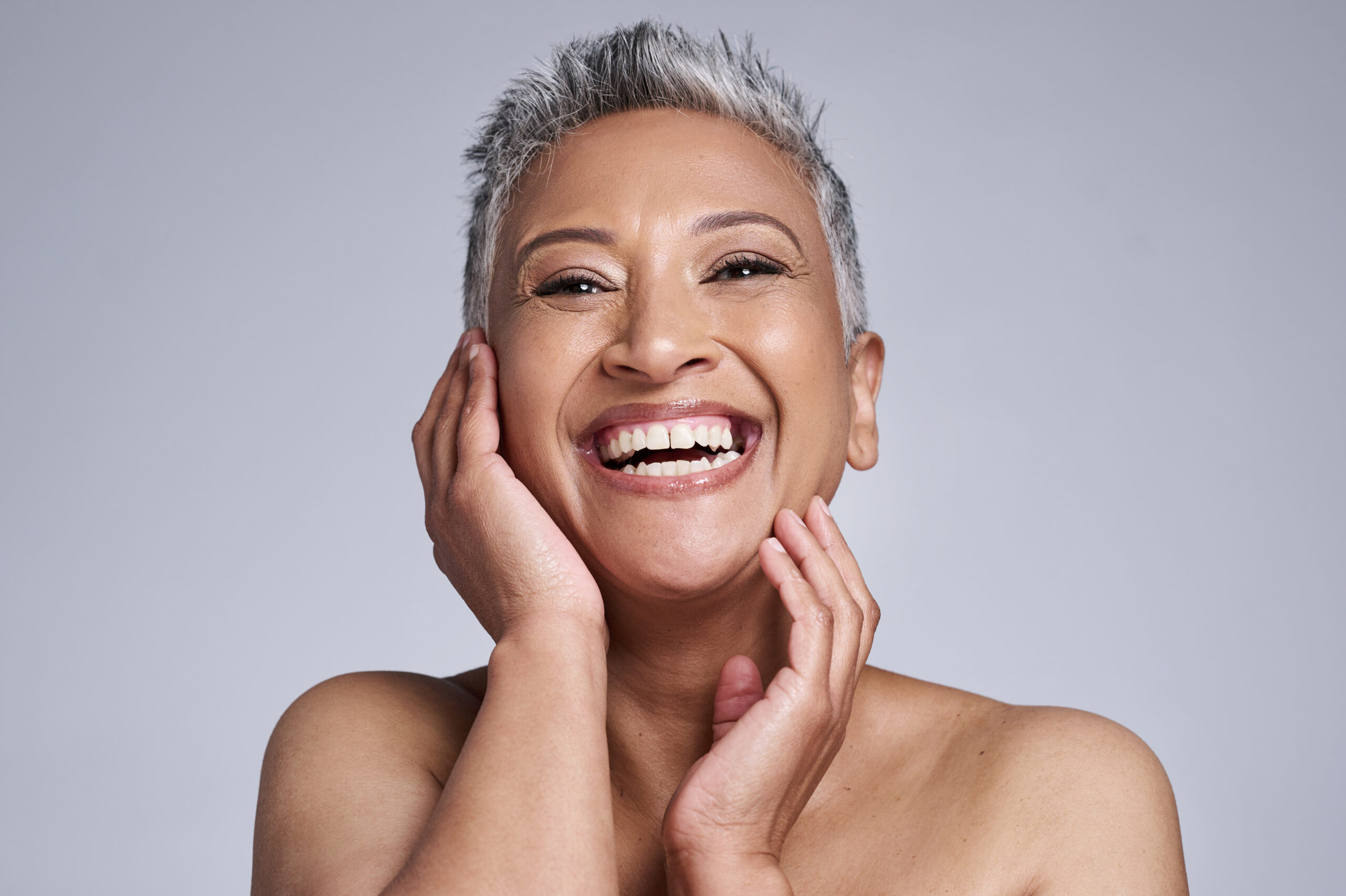 Skincare, makeup and senior woman excited about facial health, wellness and beauty against a grey mockup studio background. Smile, happy and face portrait of an elderly model for dermatology.