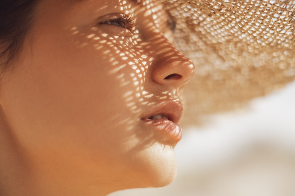 Beach woman in sun hat with shadows on face